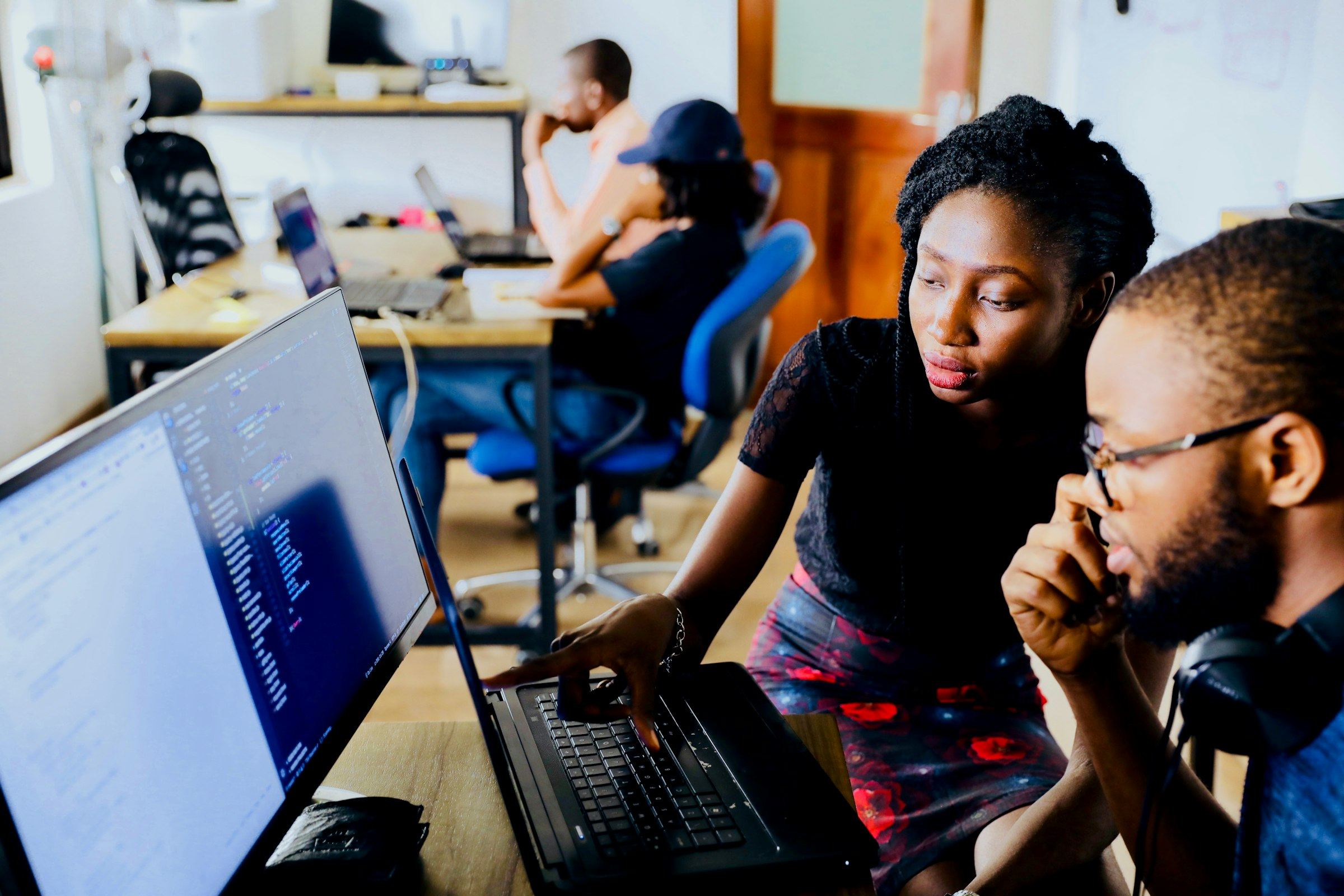 Two people look at code on a laptop screen together
