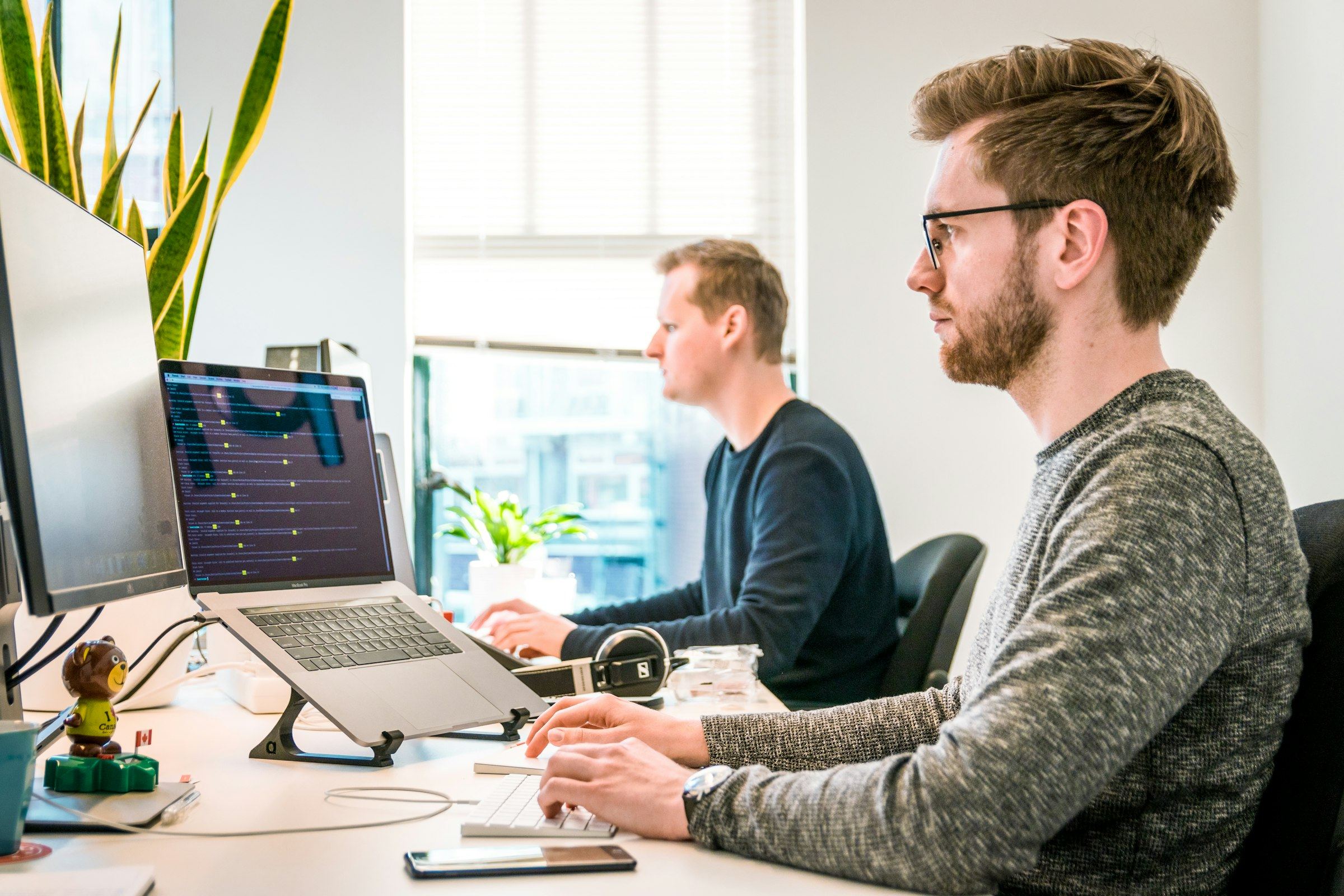 People work at laptops in a bright open office